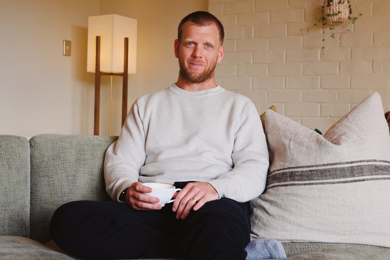 Austin, founder of PEAK, sitting on a sofa with a cup of coffee